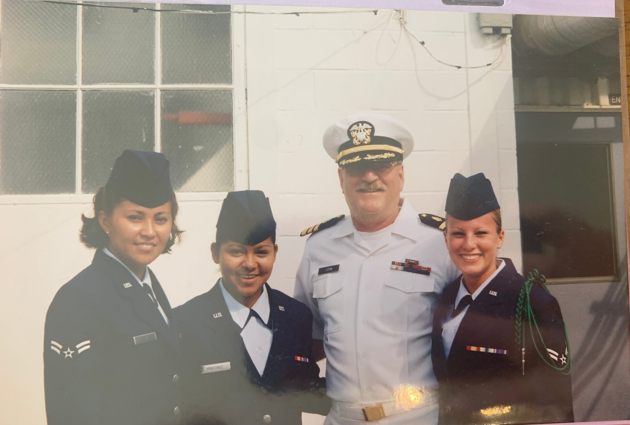 Group of U.S. military personnel in dress uniforms posing outdoors in front of a building.