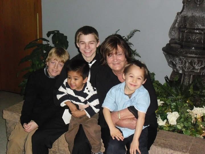 Family of five posing together indoors, smiling for a group photo near a fountain and plants.