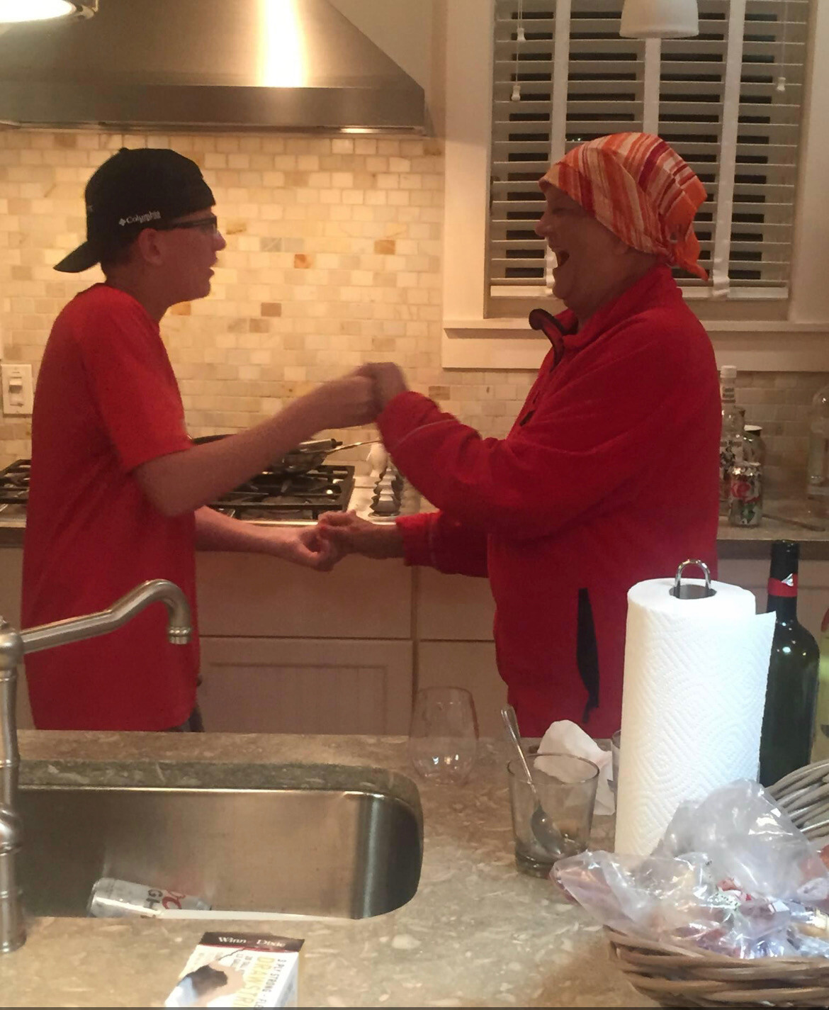 Two people in a kitchen fist-bumping and smiling at each other.