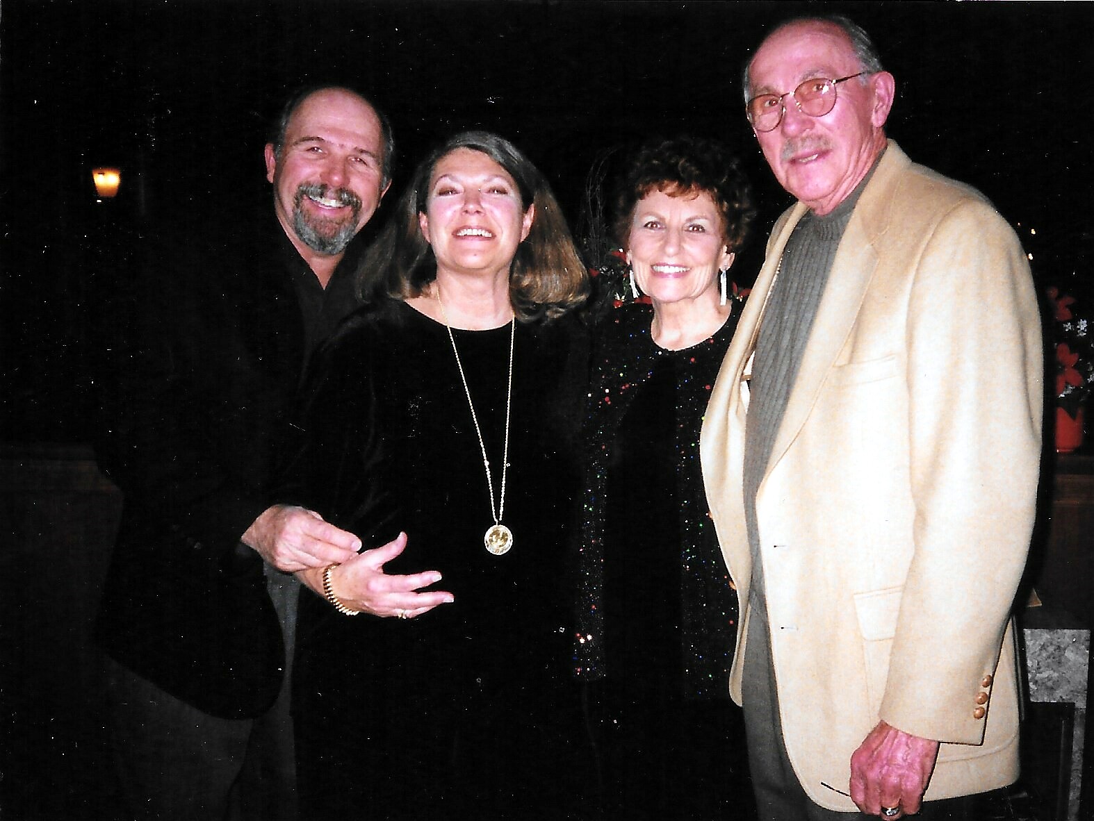 Group of four adults posing together at night, smiling for the camera.