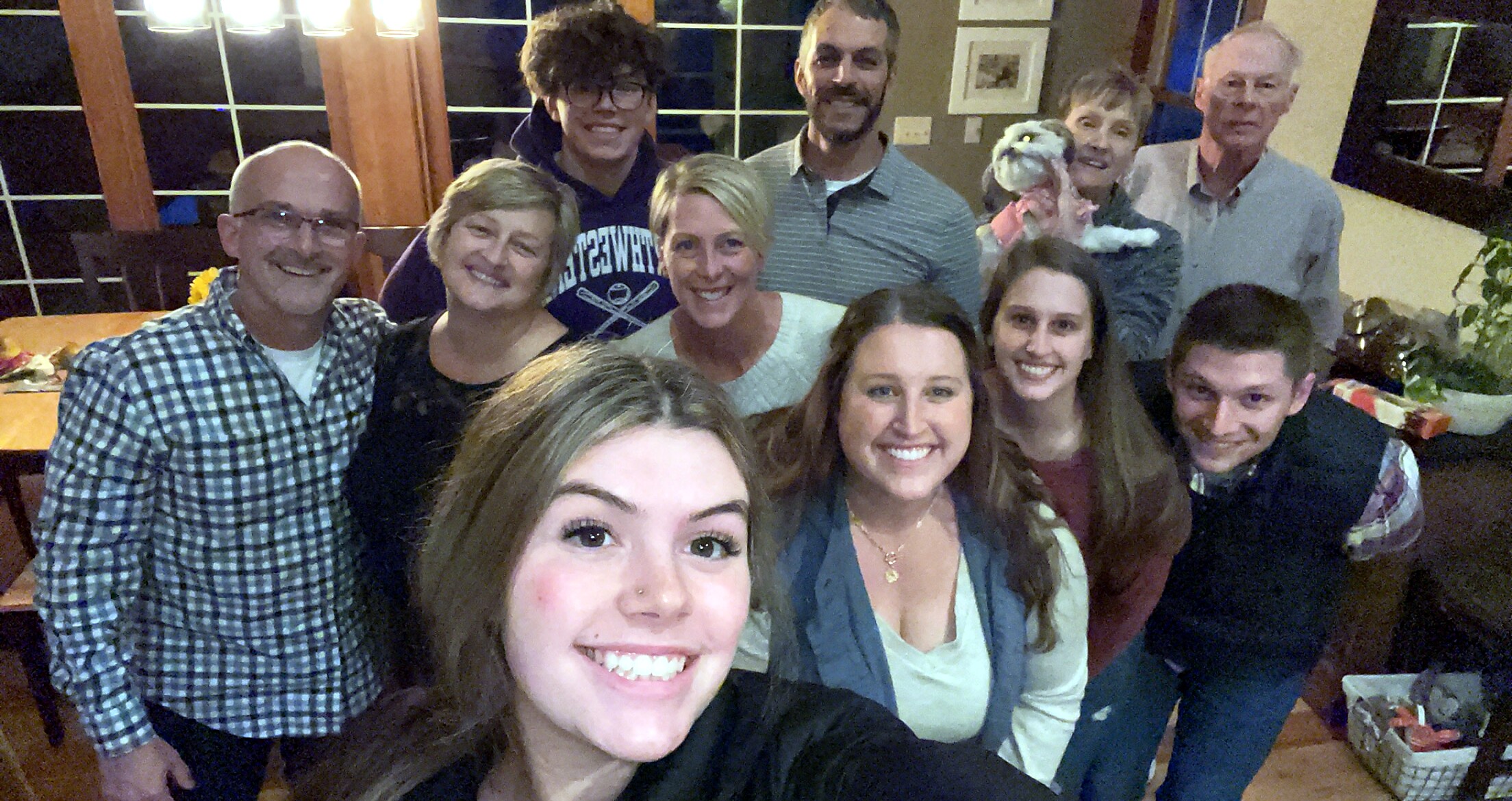 Group of smiling friends posing for a selfie at a casual indoor gathering.