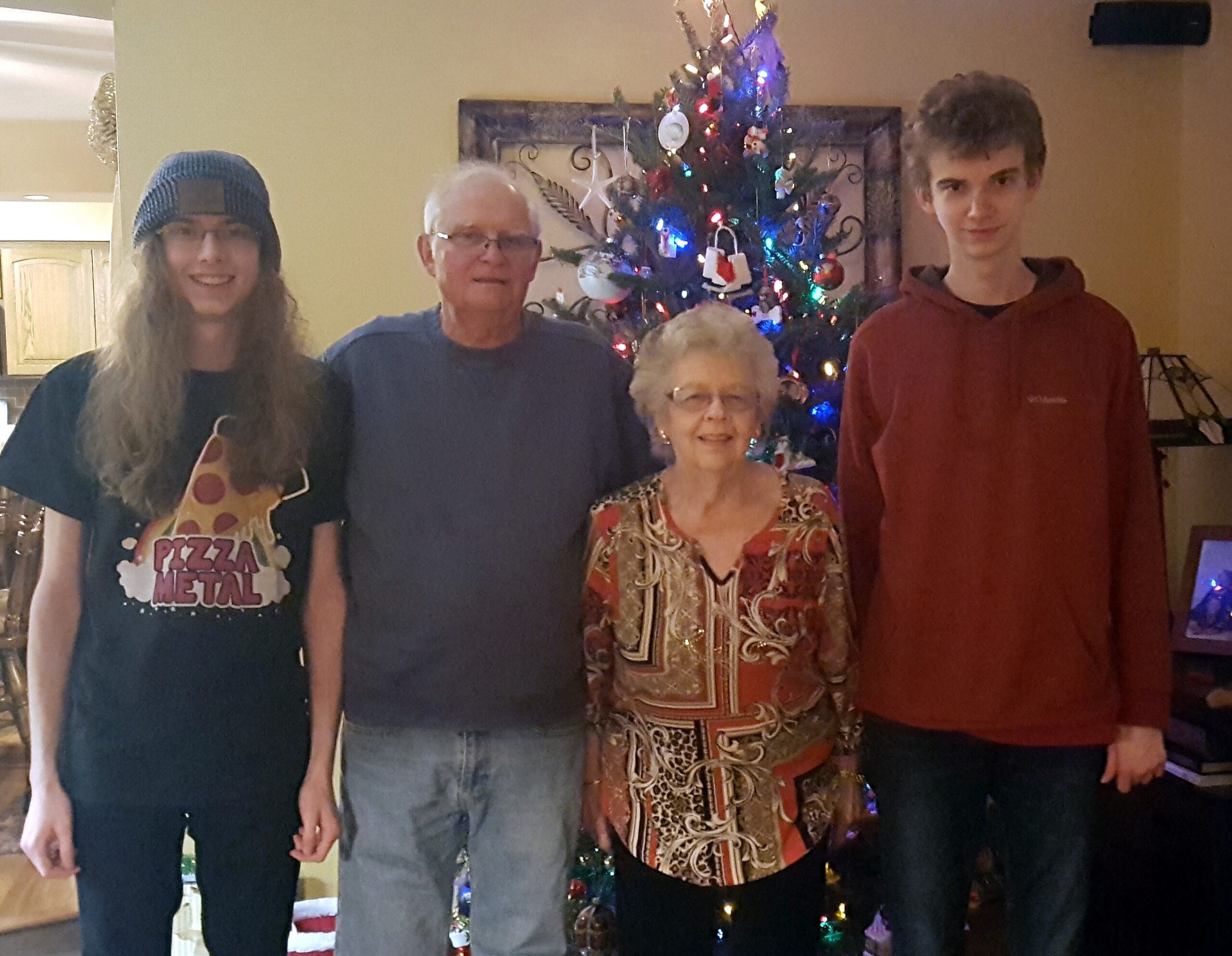Four people posing together in a living room with a Christmas tree in the background.