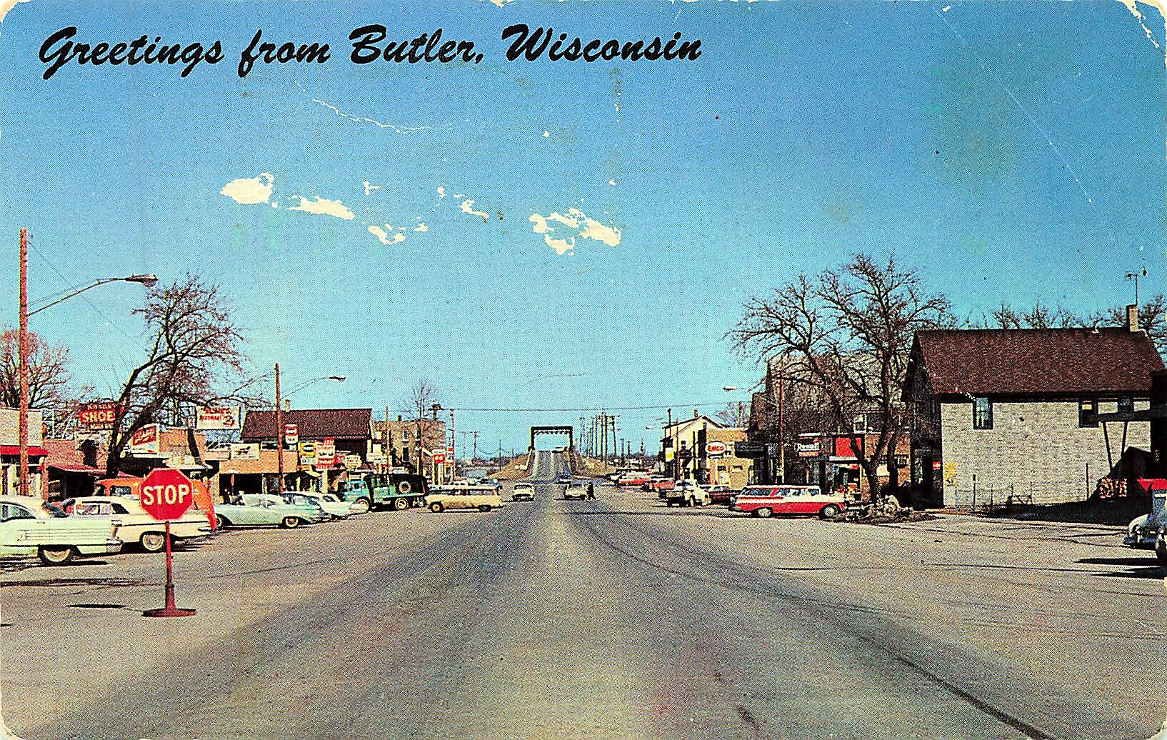 Postcard-style street scene in Buder, Wisconsin with vintage cars, storefronts, and a red Stop sign under a blue sky.