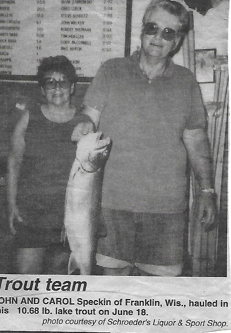 Two anglers pose with a large lake trout in a newspaper photo about a fishing team, weight shown as 10.68 lb in the caption.