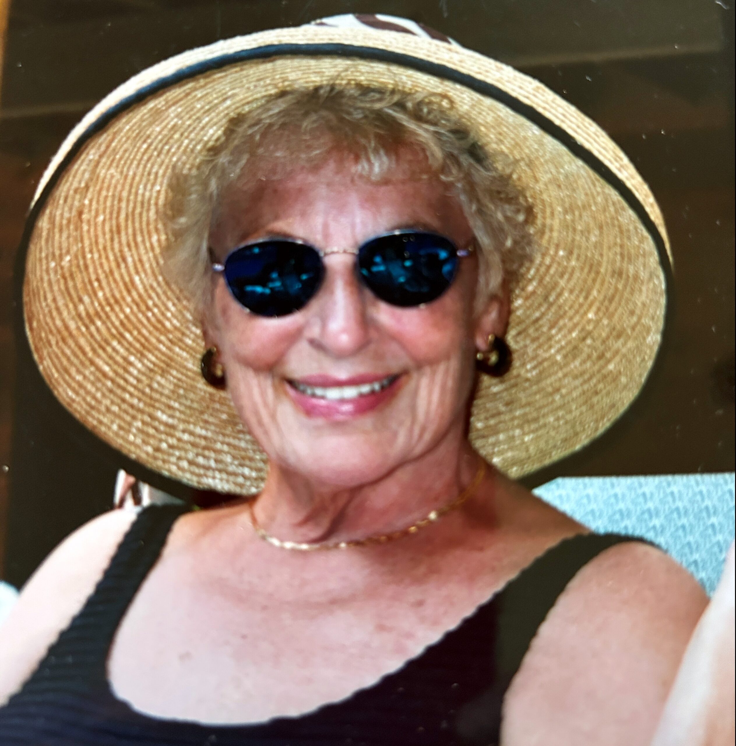 Person wearing a large straw hat and dark sunglasses, smiling at the camera.