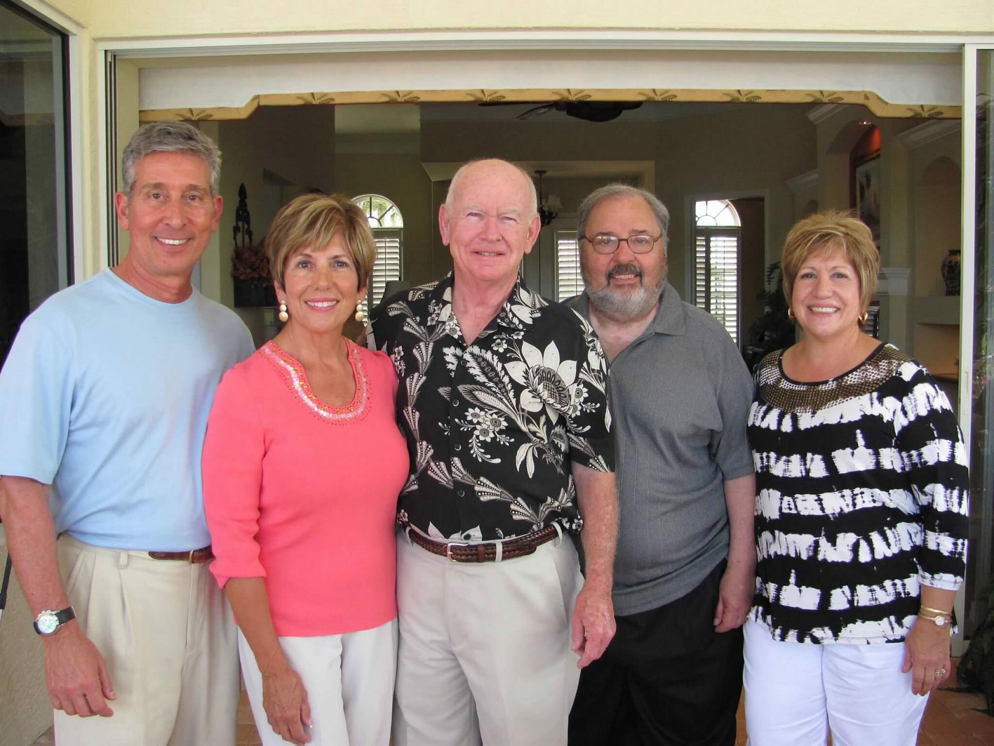 Five adults stand together in a doorway, smiling for a group photo.