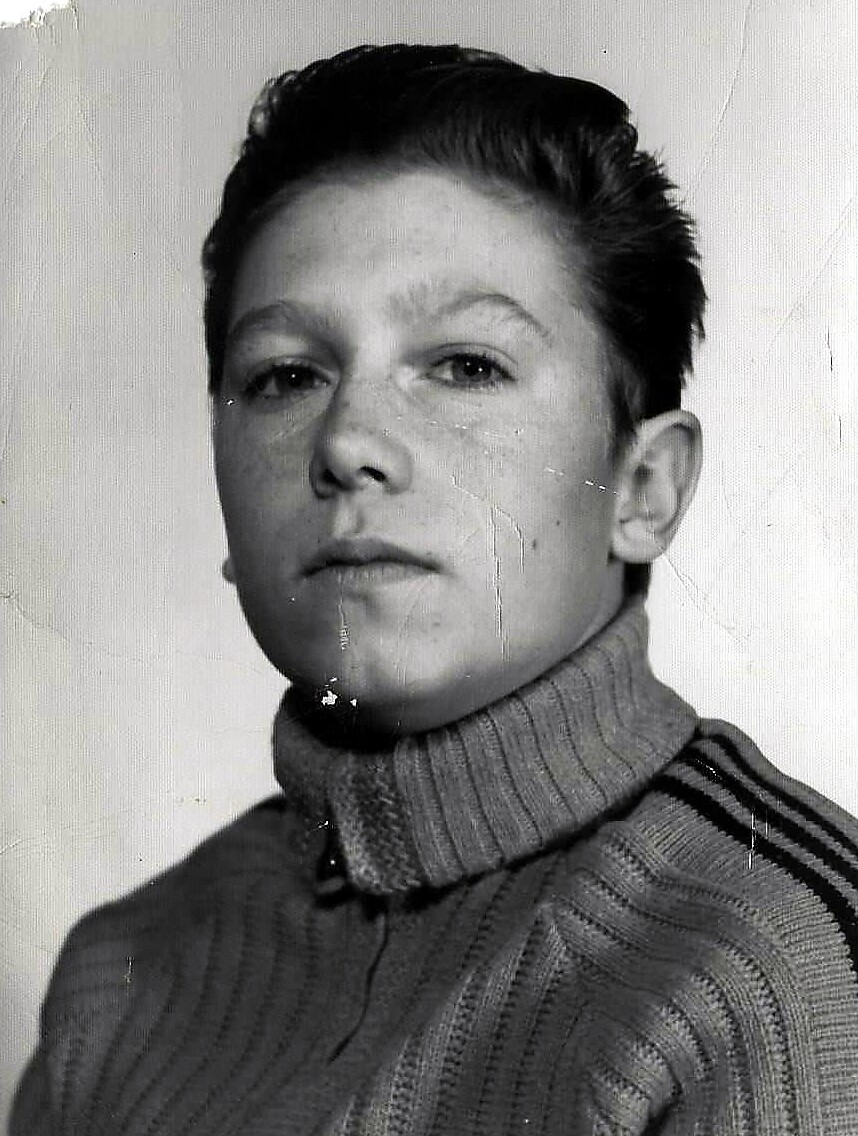 Portrait of a young boy with short dark hair wearing a ribbed turtleneck sweater in black and white.