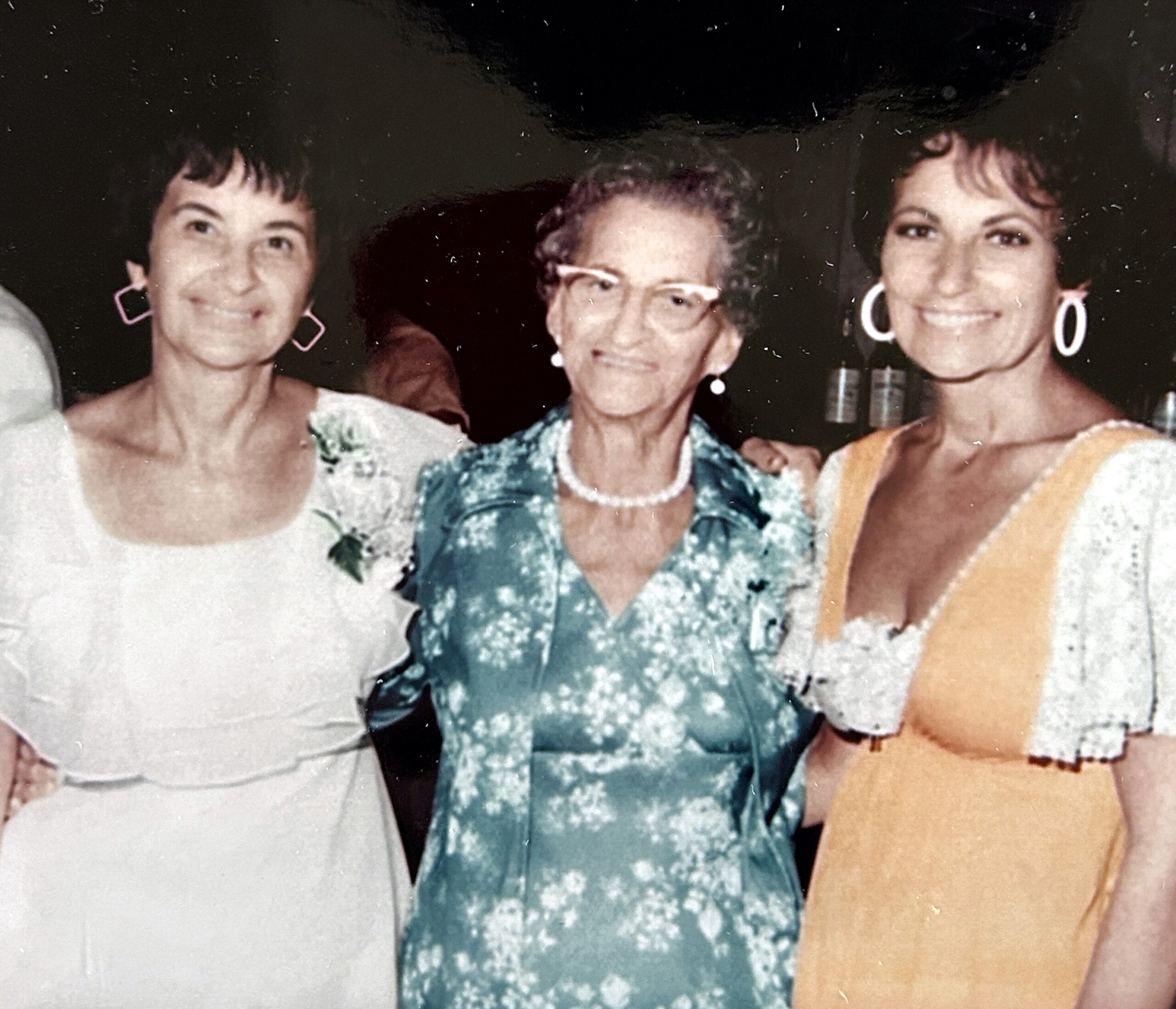 Three women posing together and smiling for a photograph at a formal event.