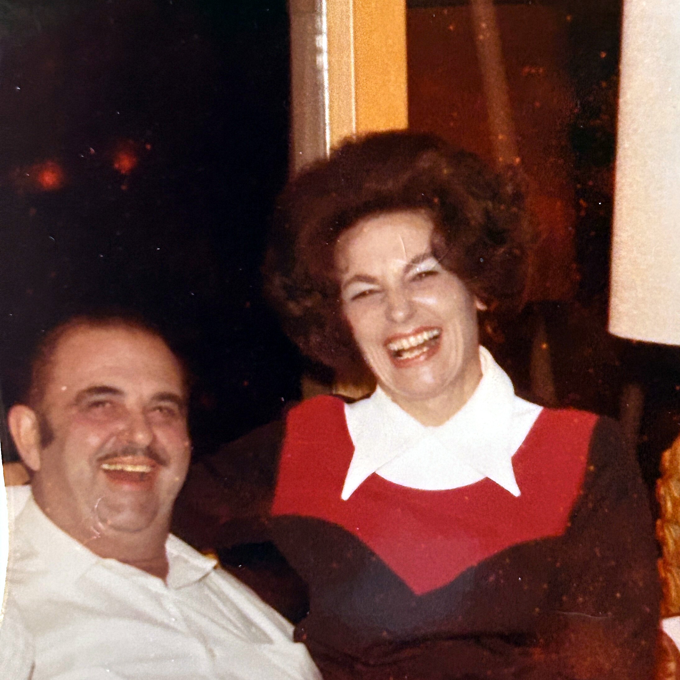 Two friends posing for a candid group photo, smiling widely indoors.