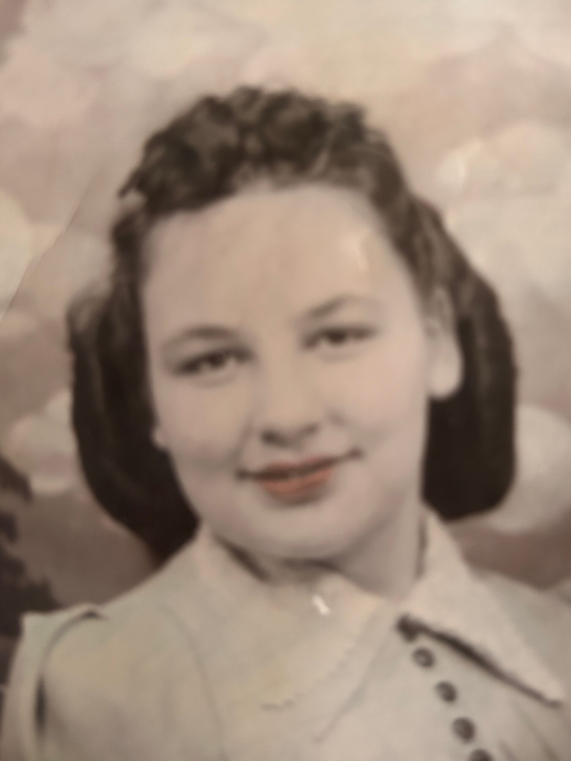 Close-up portrait of a person with dark hair wearing large earmuff-style headphones in a sepia-toned photo, looking at the camera.