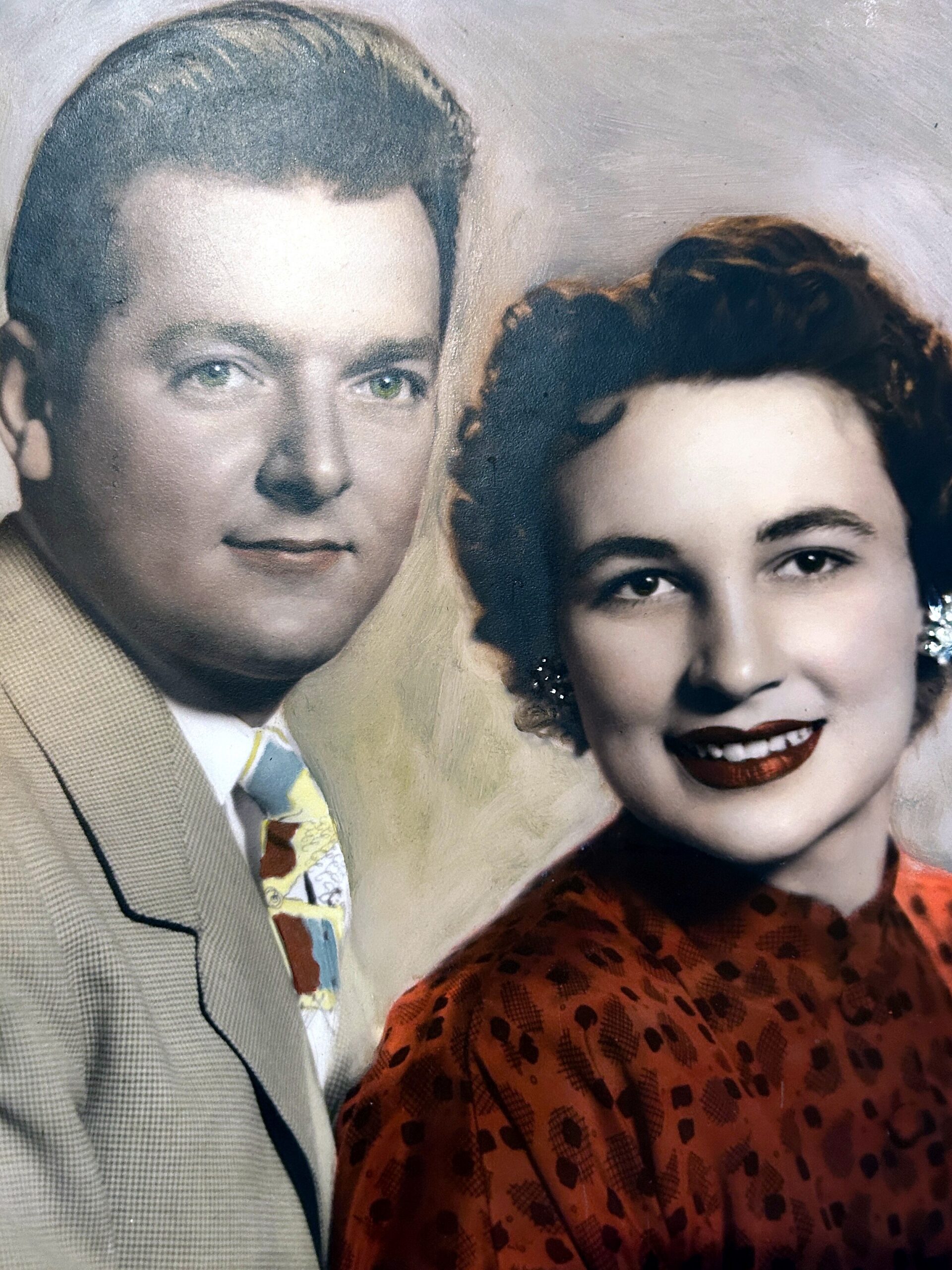 Vintage painted portrait of a man in a tan suit and a woman in a red patterned dress, posing closely together.