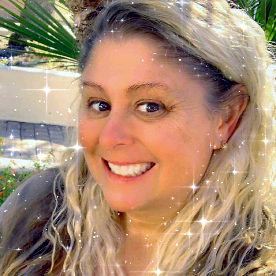 Smiling woman with long blonde hair outdoors, with a sparkle filter.