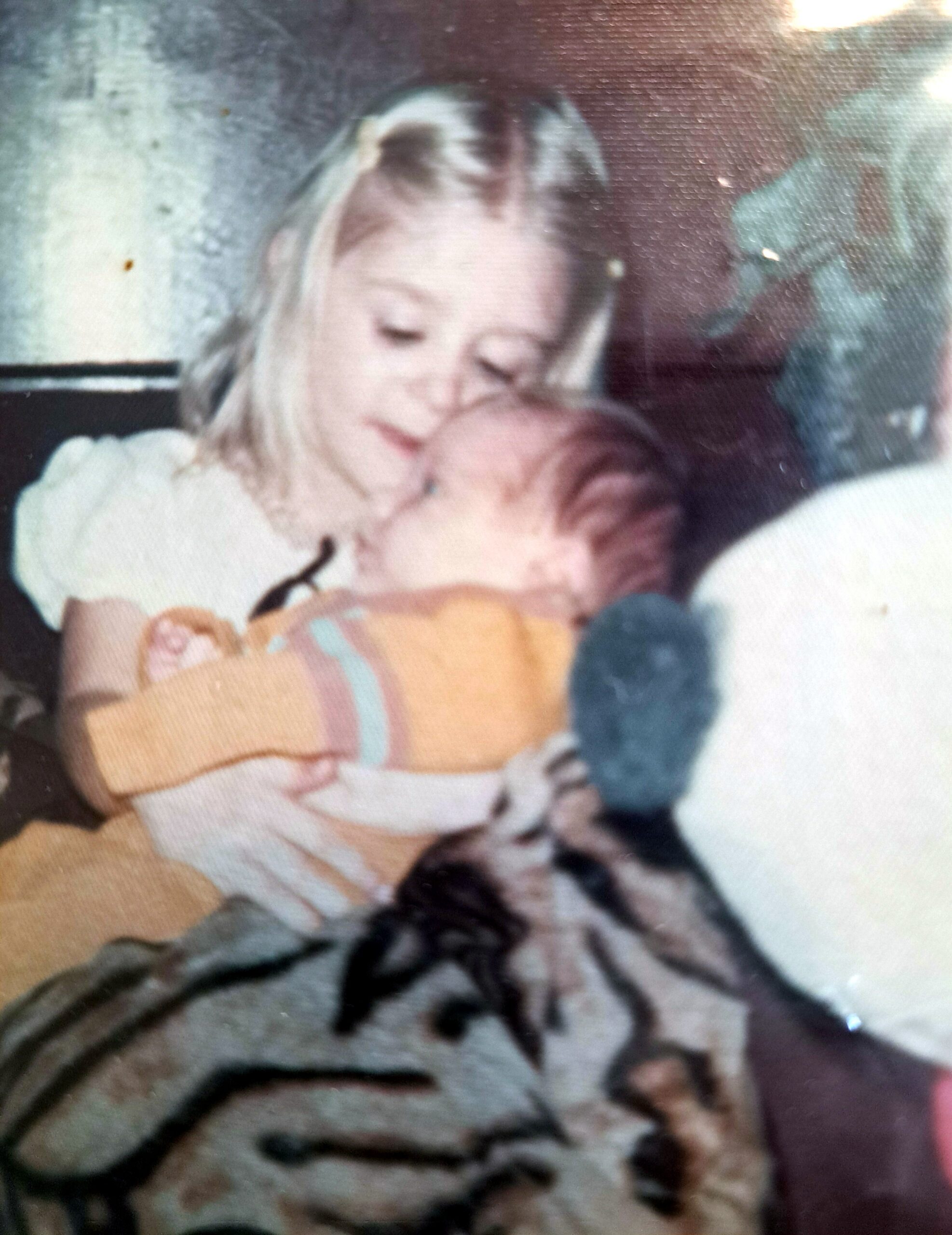 Close-up of a baby sleeping with eyes closed, hand near its mouth on a tiger‑print blanket.
