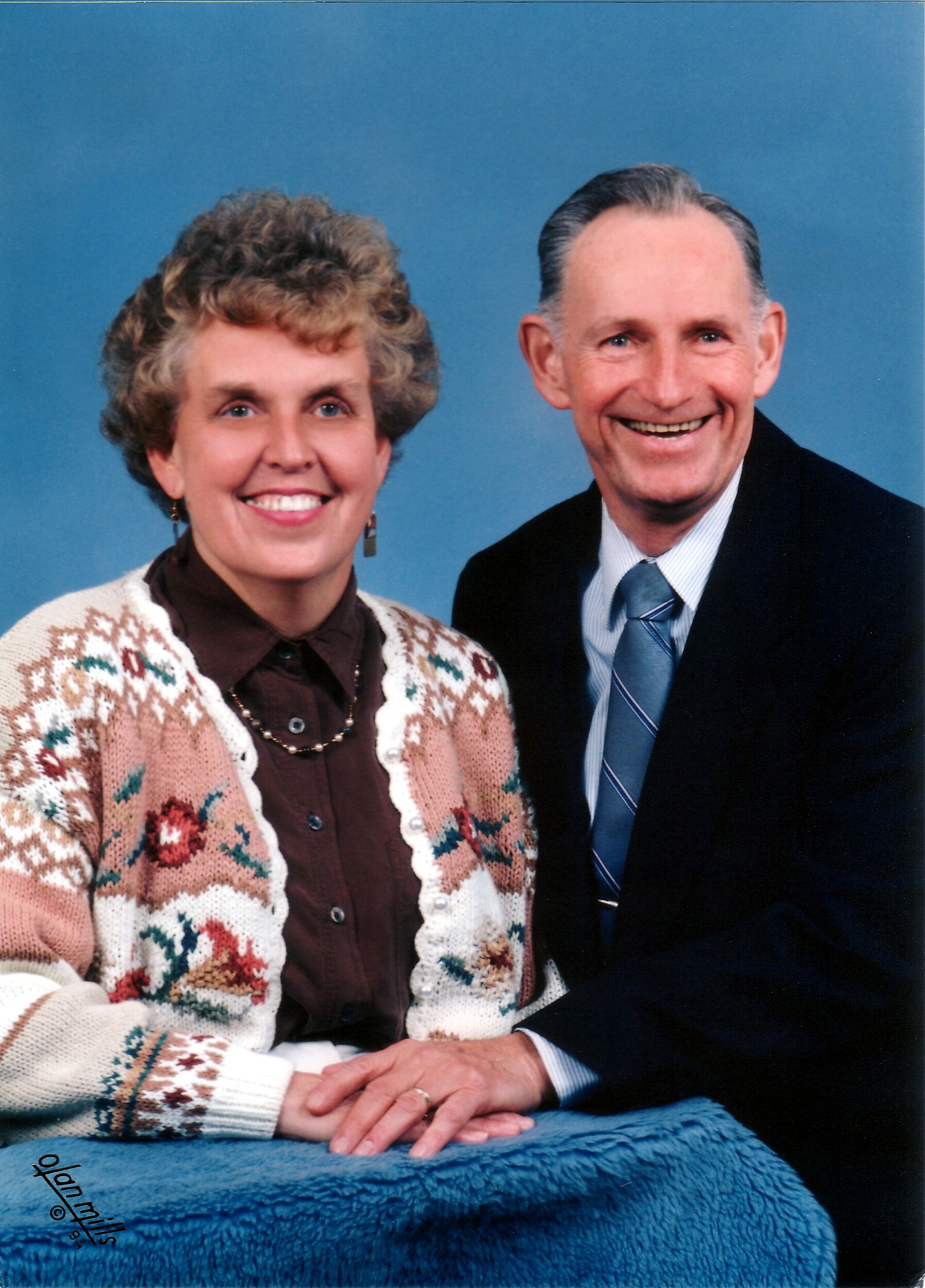 Smiling older couple posing for a studio portrait against a blue background.