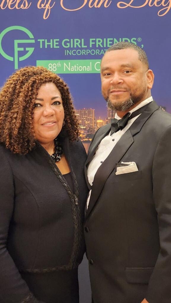 Couple in formal attire posing for a photo at a Girl Friends event backdrop crowning a gala moment.