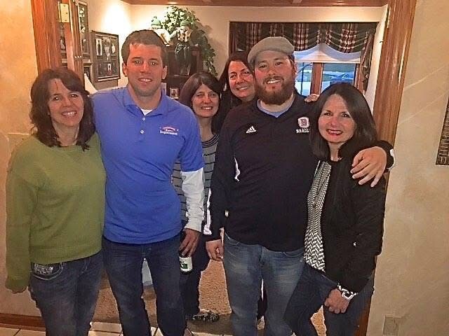Six adults standing together in a home entryway, smiling for a group photo.