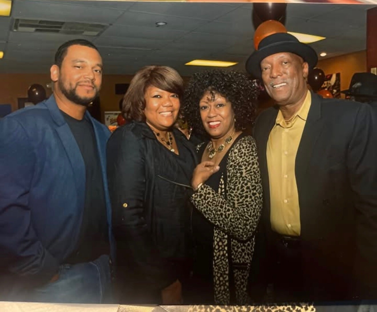 Four adults posing together at a social event, smiling for the camera.