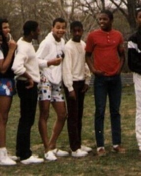 Group of diverse friends standing together outdoors in a park, posing for a photo on the grass.