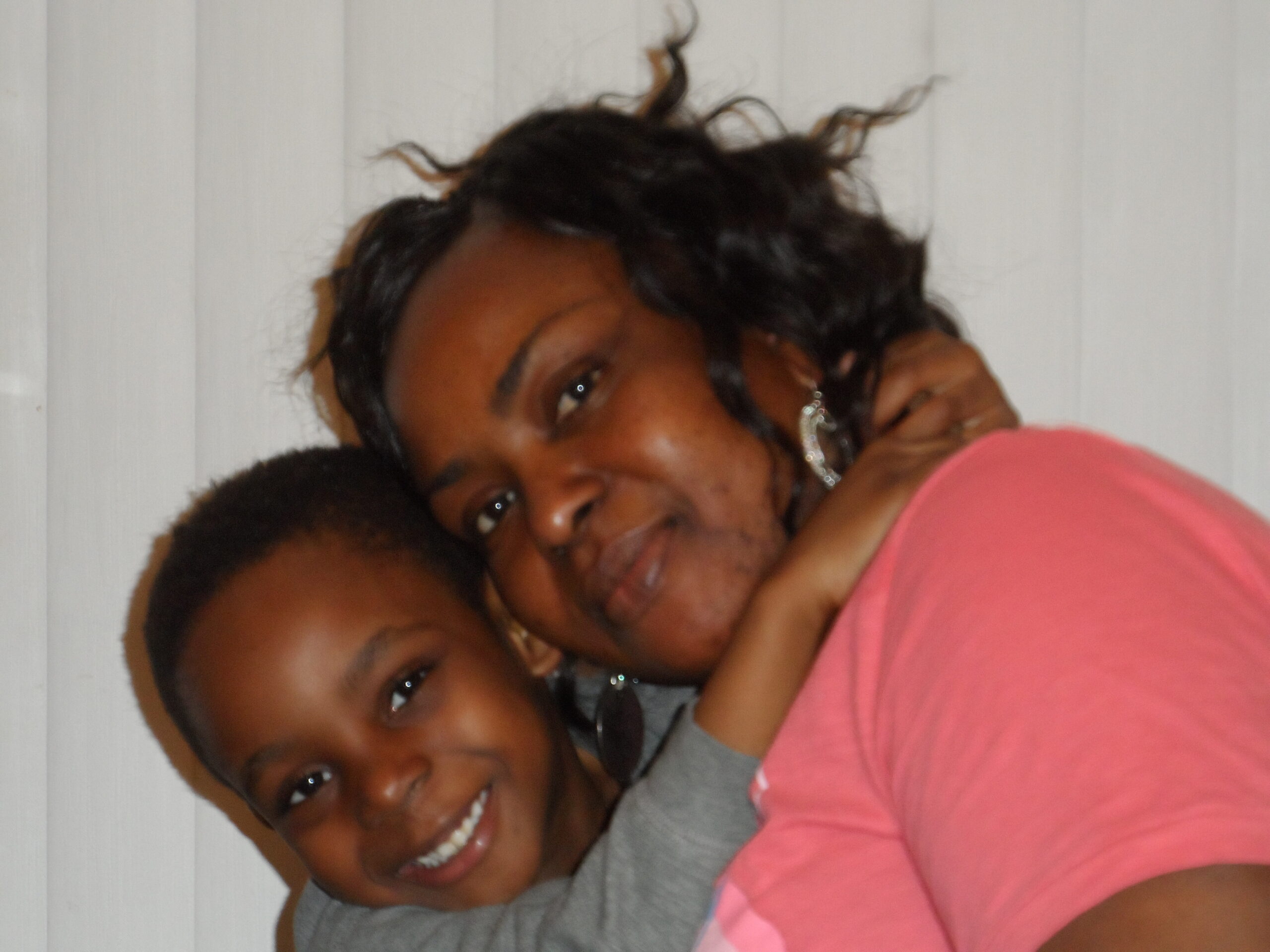 Two people smiling and hugging each other in a close-up pose.
