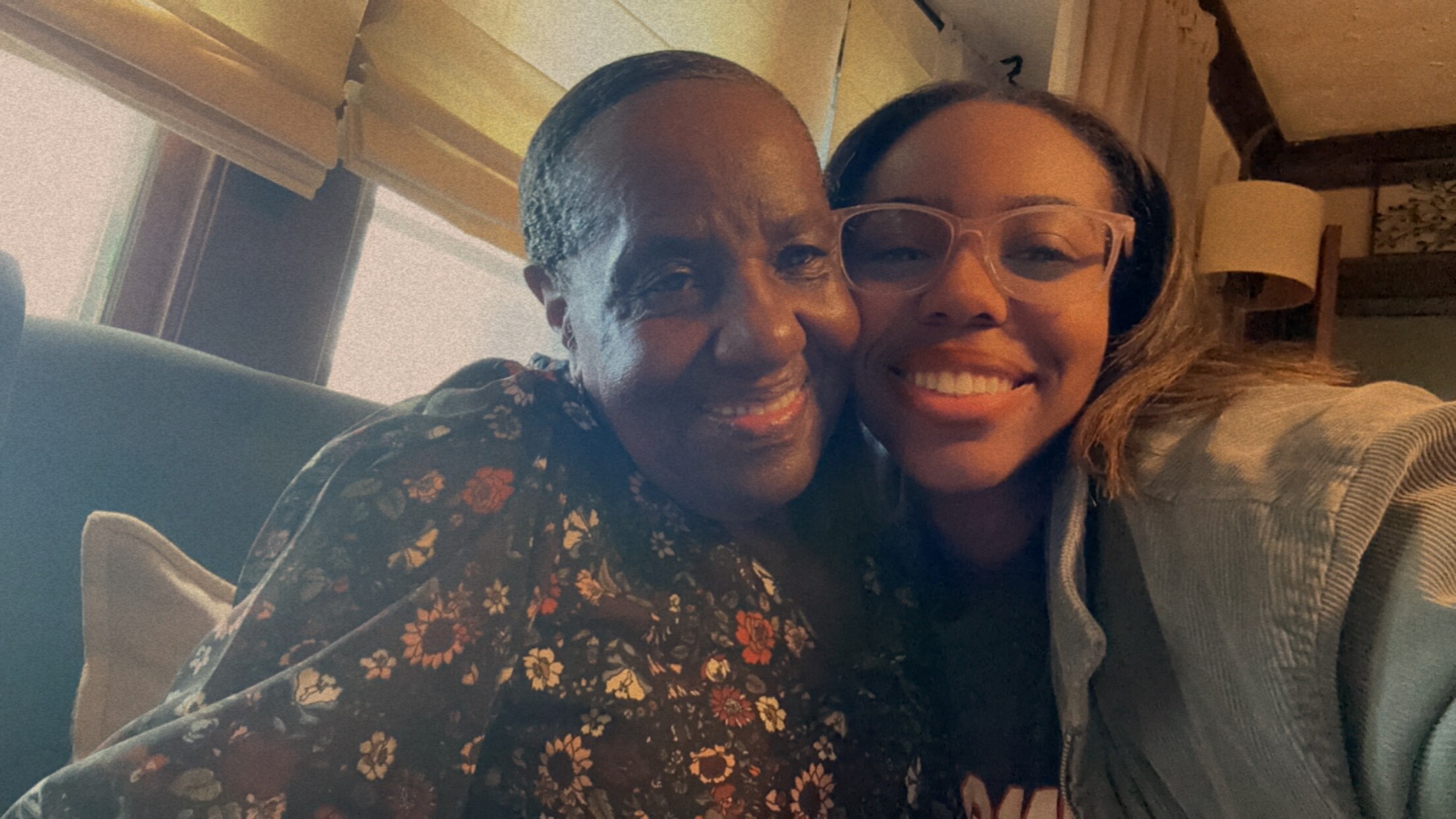 Two people smiling and hugging on a sofa in a cozy living room, capturing a warm moment together.