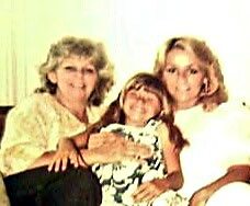 Three generations of women posing together for a family photo, with a child in the center and two adults on either side.