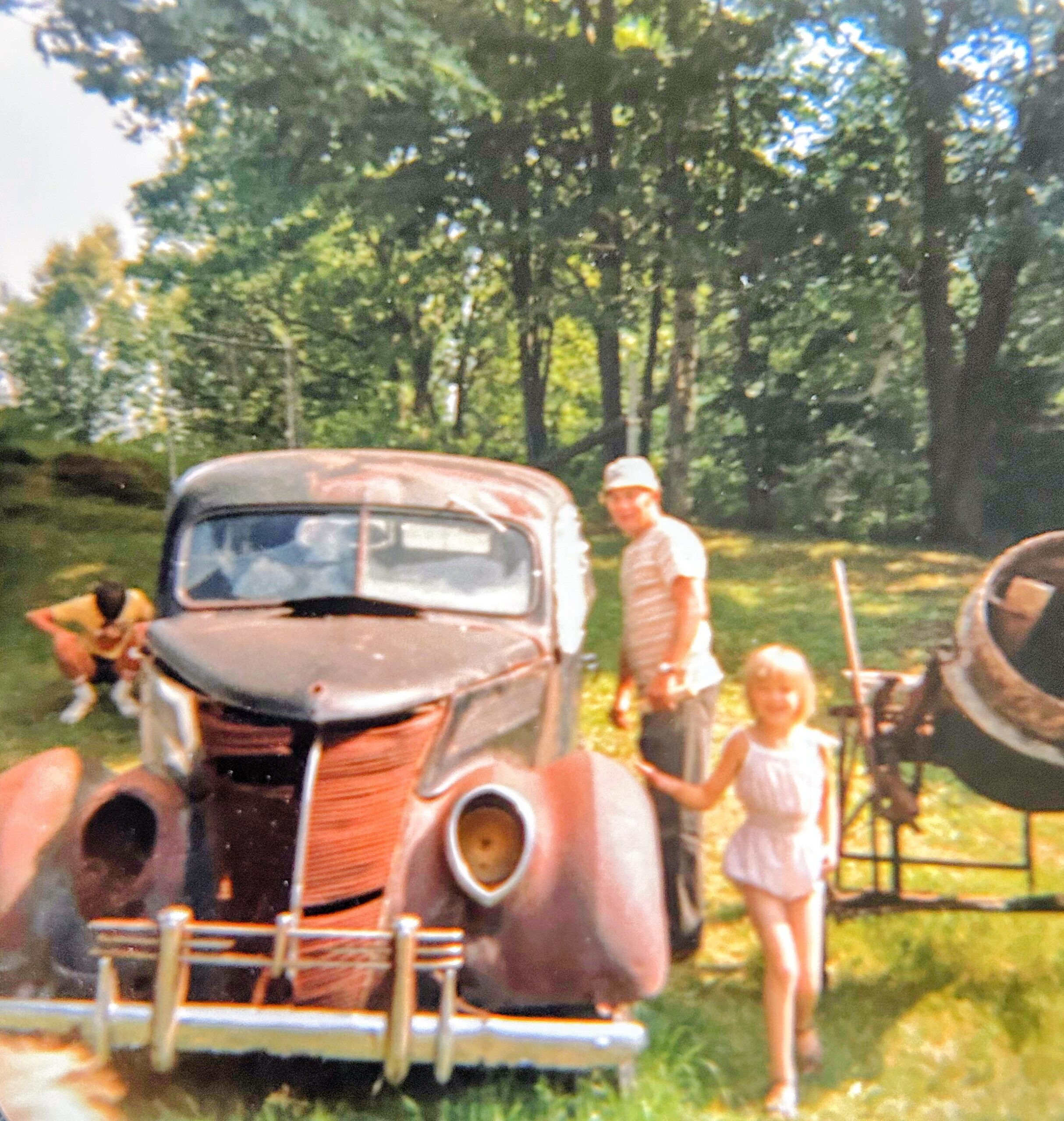 Blurry photo of an old rusty truck outdoors with several people standing around.
