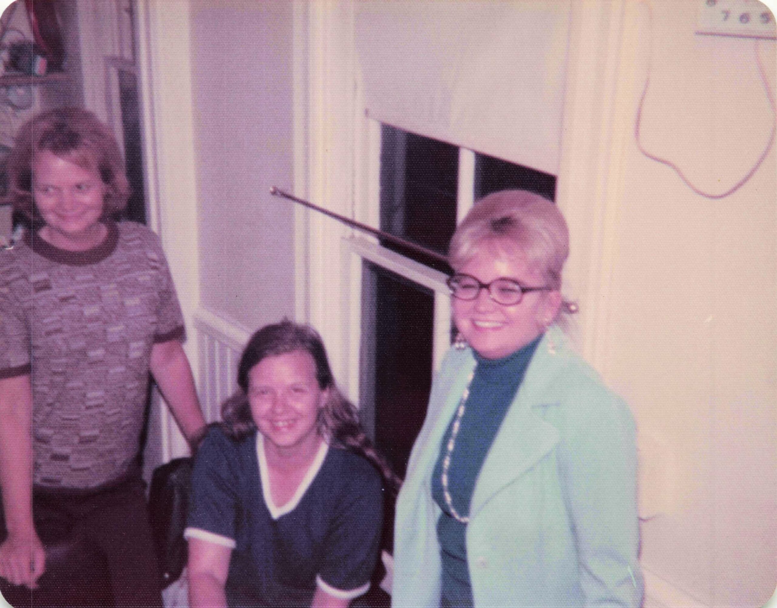 Group of people posing in a doorway, smiling at the camera (two adults and a child).