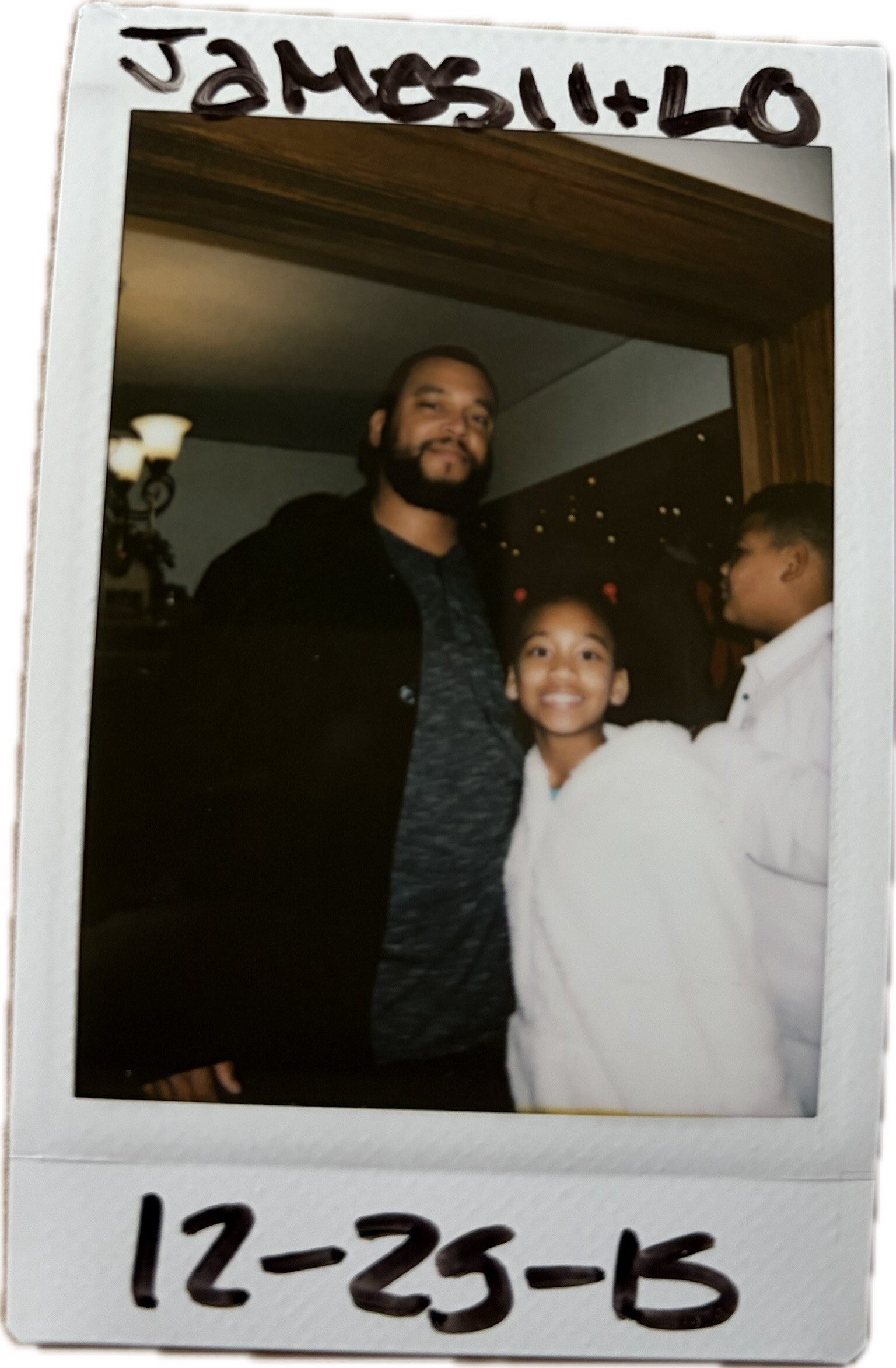 Polaroid photo of a bearded man with a smiling young girl indoors at a gathering, handwritten caption visible at the top