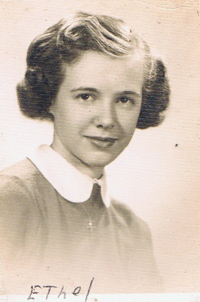 Black-and-white studio portrait of a young woman with short curled hair, wearing a white-collared blouse; signature 'Ethel' at the bottom.