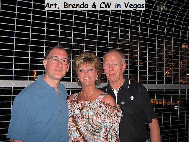 Three adults pose together in front of a metal grid fence at night; overlay text reads 'Art, Brenda & CW in Vegas'.