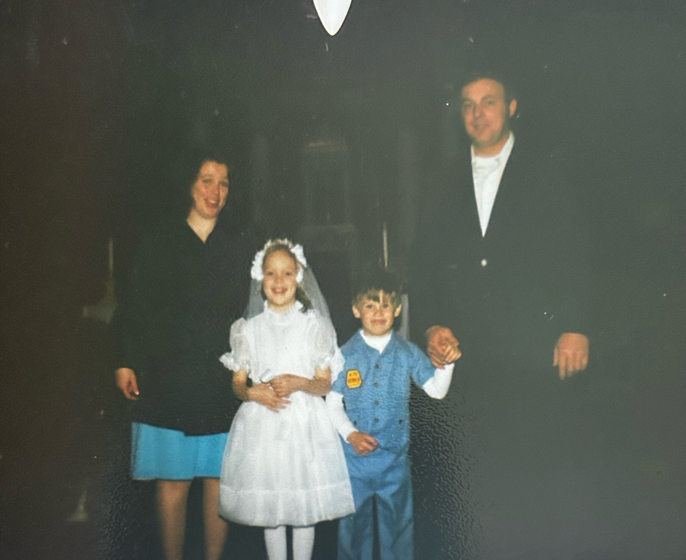 Bride in a white wedding dress posing with family and children at a formal group photo.