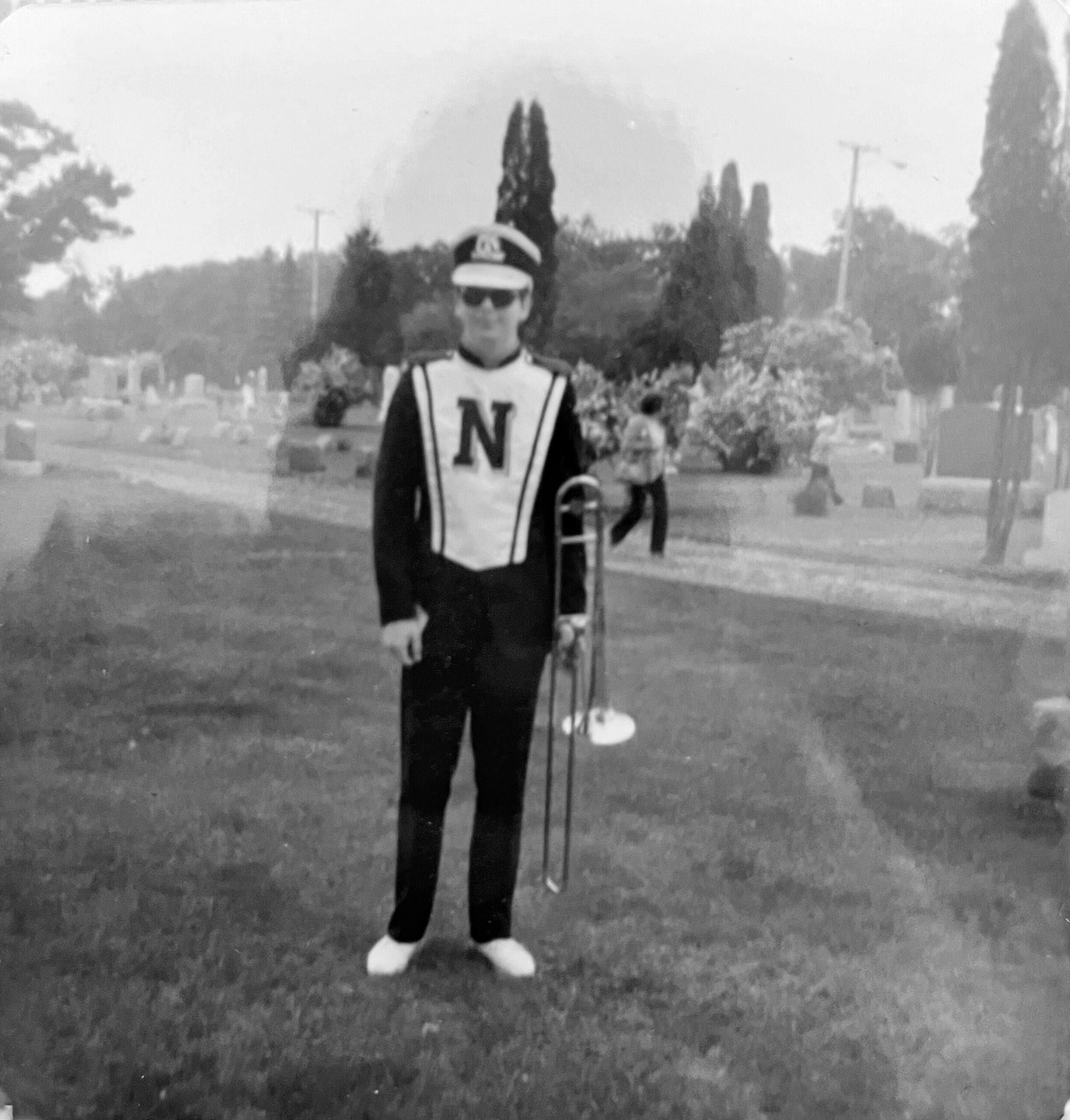 Person in a marching band uniform holding a baton, standing on a field; large N on chest plate and peaked hat.