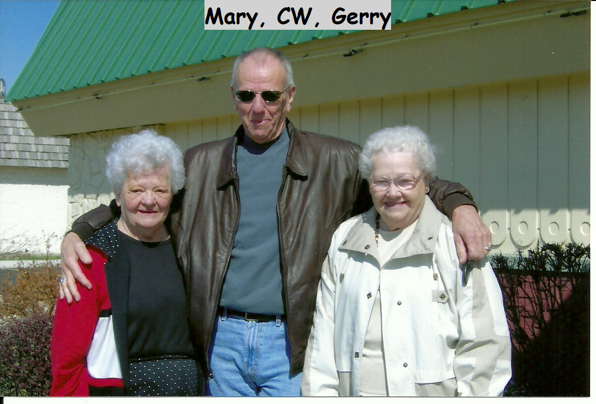 Three seniors pose together outdoors with the man in the center having his arms around the two women; caption reads 'Mary, CW, Gerry'.