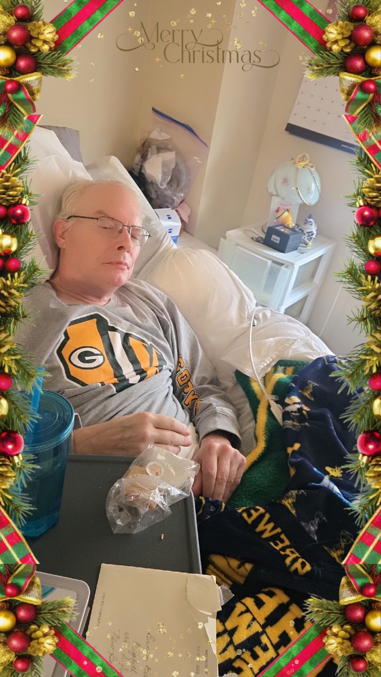 Older man with glasses resting in a hospital bed, covered with a blanket, Christmas border around the scene.