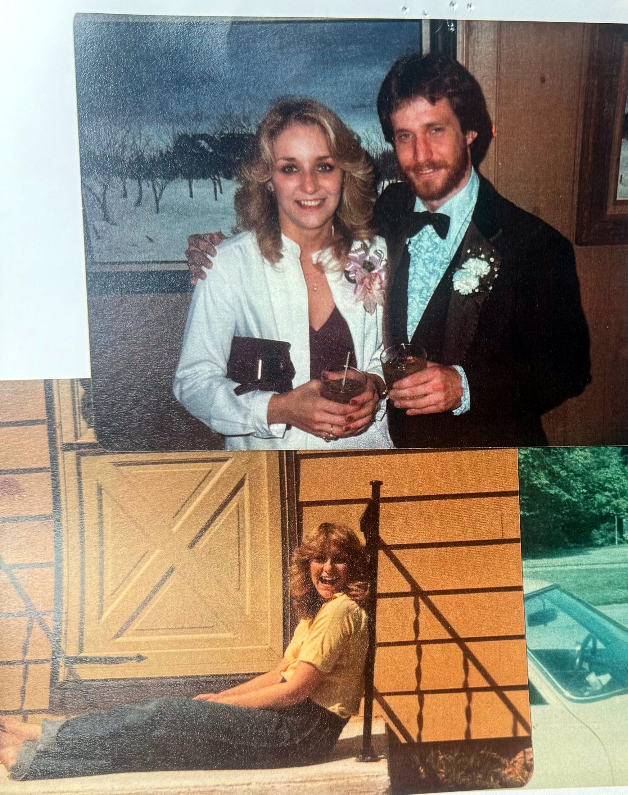 Smiling couple in formal attire posing with drinks at a party; woman in a white blazer, man in a tuxedo with bow tie.