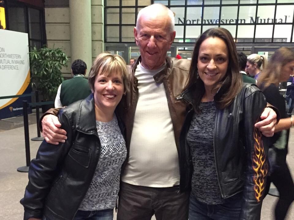 Three people smile for a photo indoors, with a man in the middle flanked by two women, their arms around each other near a Northwestern Mutual backdrop.