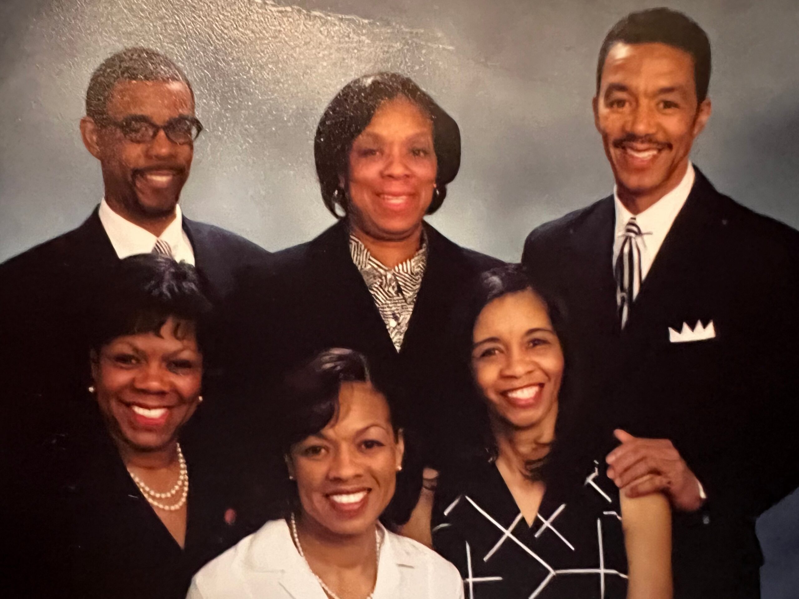 Smiling group of adults in formal attire posing for a group portrait indoors.