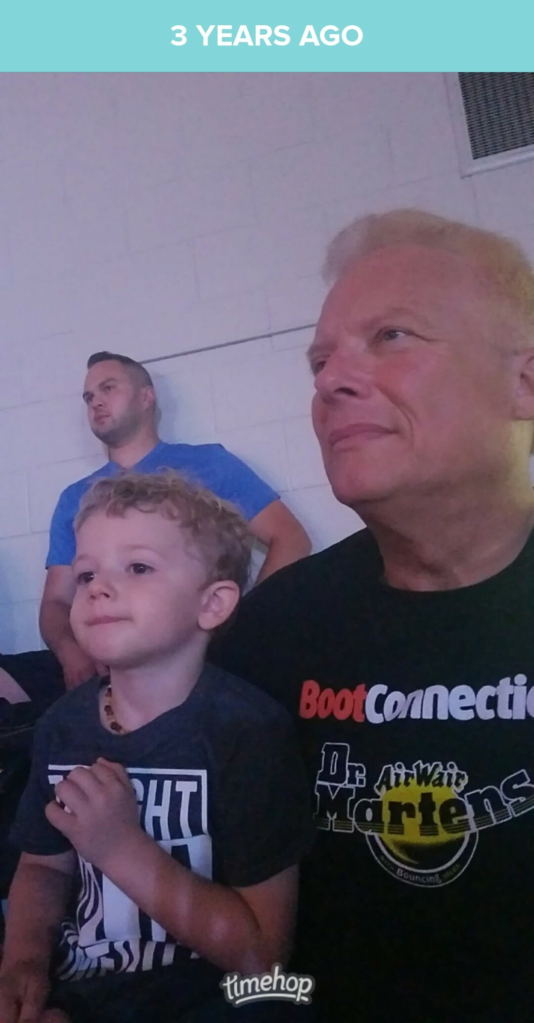 Three people posing in a room: a man in a black shirt at right, a smiling young boy in front, and another man in a blue shirt in the background (caption: 3 YEARS AGO).