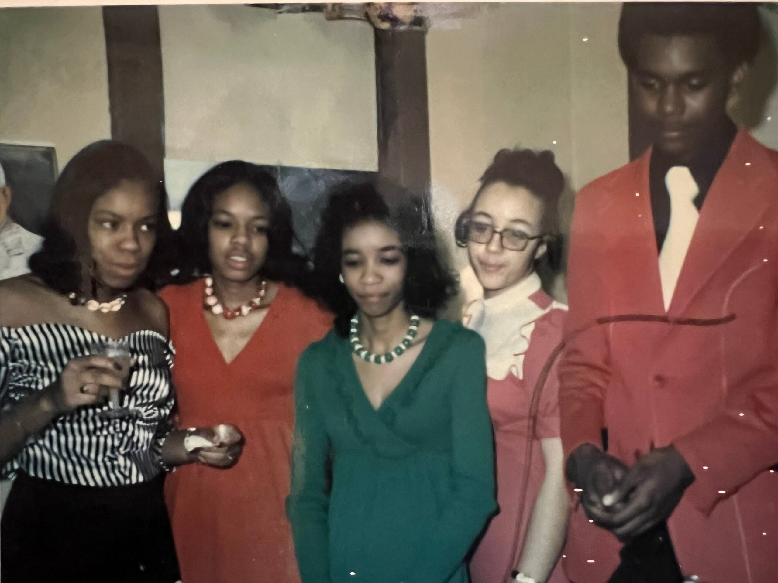 Group portrait of young people in colorful formal attire posing together at a social gathering.