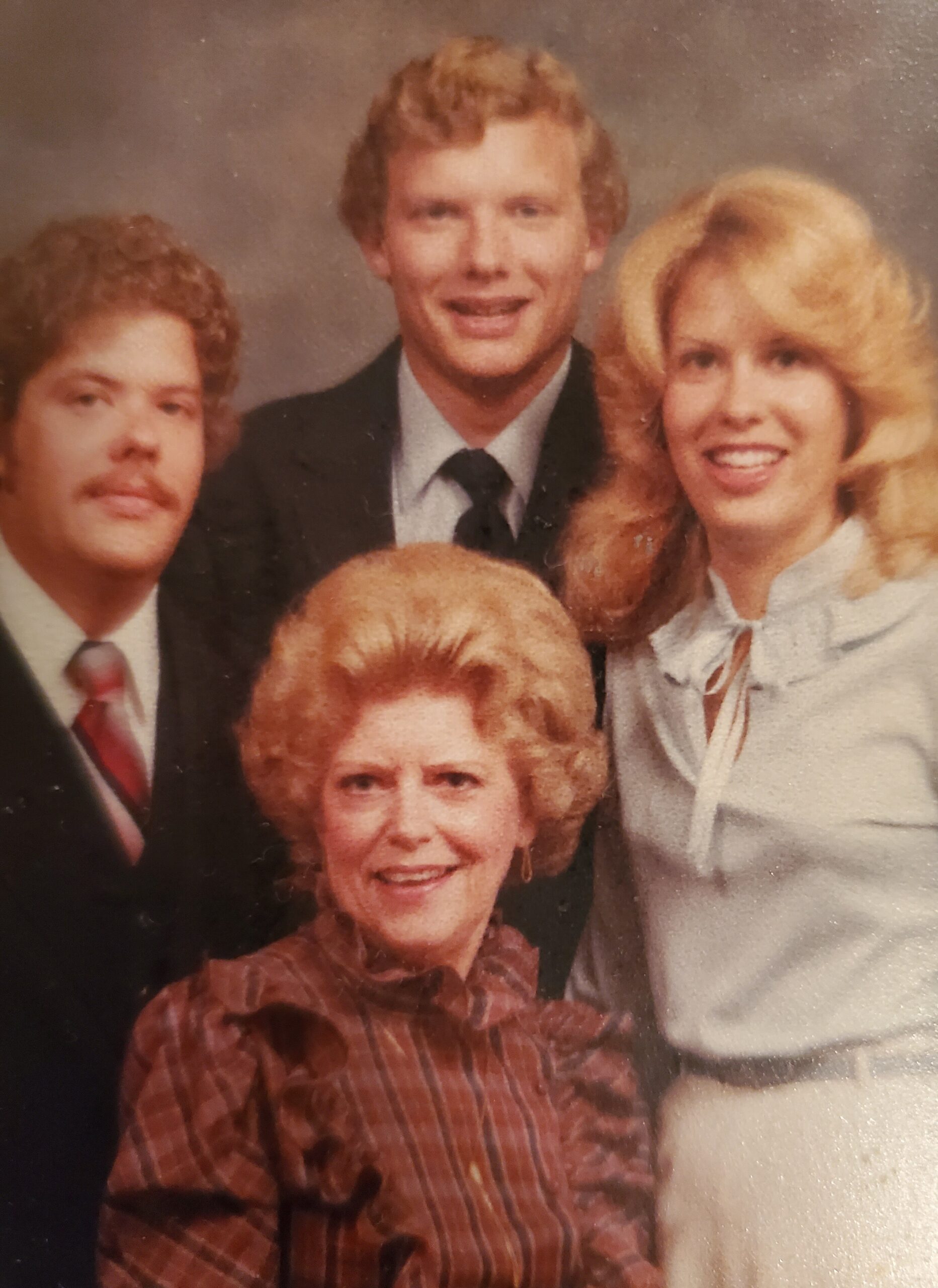 Smiling family portrait: woman in the foreground center with a man to the left and a blonde woman to the right, all in vintage attire.