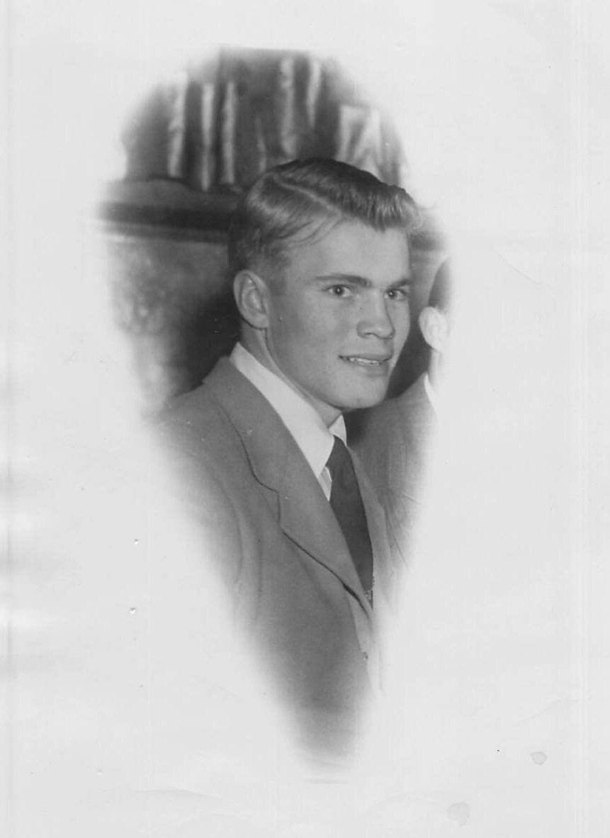 Black-and-white portrait of a young man in a suit with a slight smile.