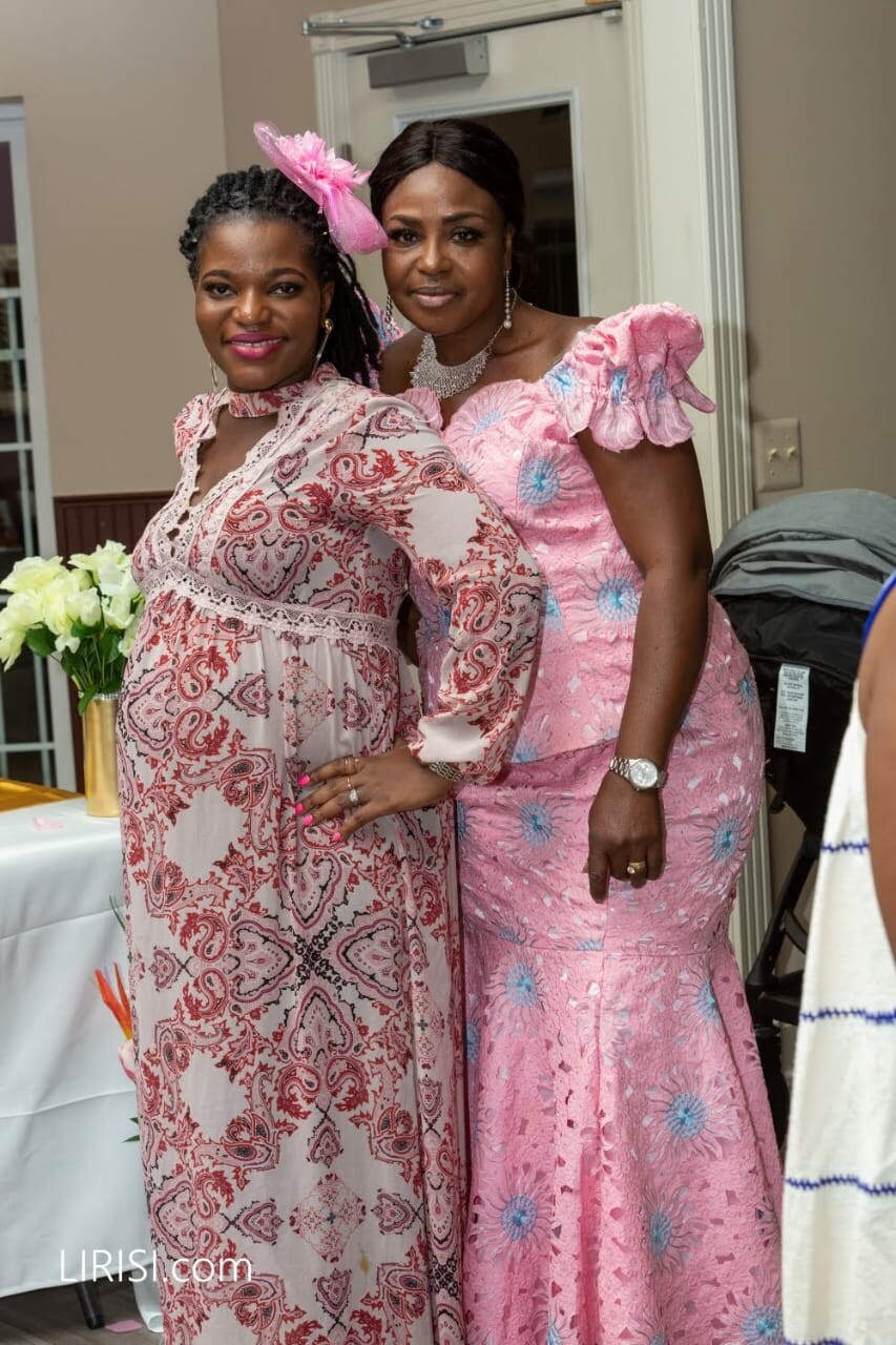 Two women in pink dresses posing together at a celebration, smiling for the camera.