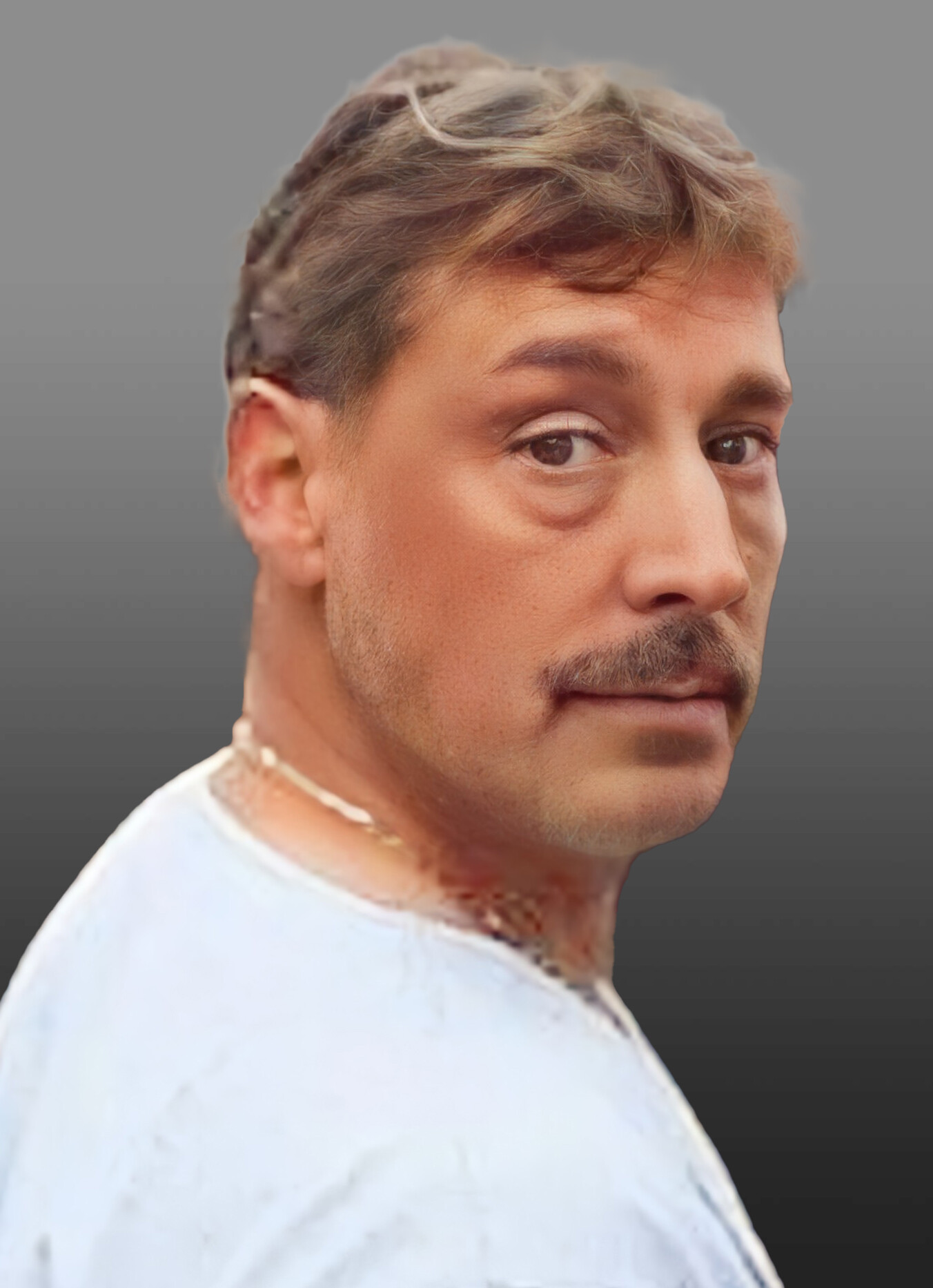 Close-up portrait of a man with light brown hair and stubble, looking over his shoulder against a gray gradient background.