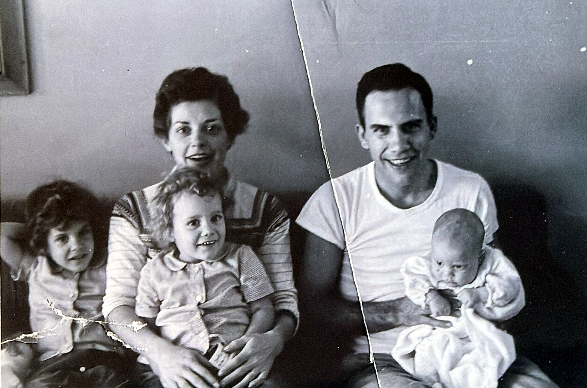 Black-and-white family portrait of a mother, father, and three young children posing together and smiling at the camera.