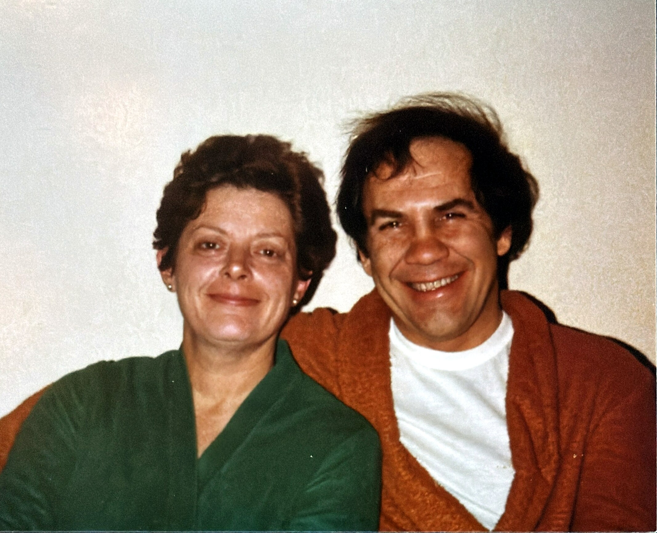 Two people smiling for a close-up photo, standing side by side with arms around each other.