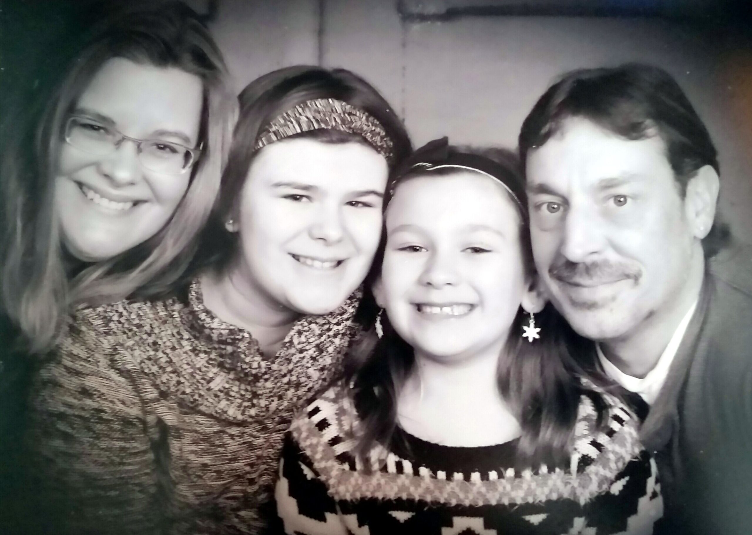Smiling family of four taking a close selfie together.