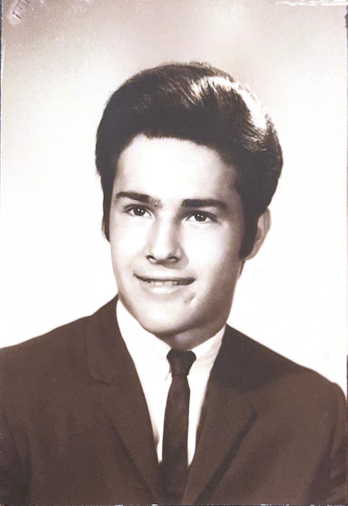 Young man in a suit and tie posing for a formal studio portrait, black-and-white.