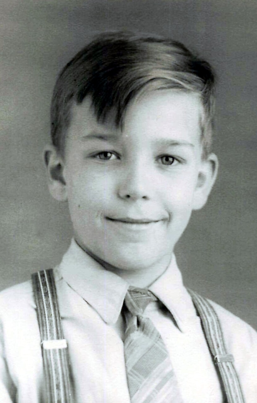 Young boy in a collared shirt with a striped tie and suspenders, smiling for a school portrait (black-and-white).