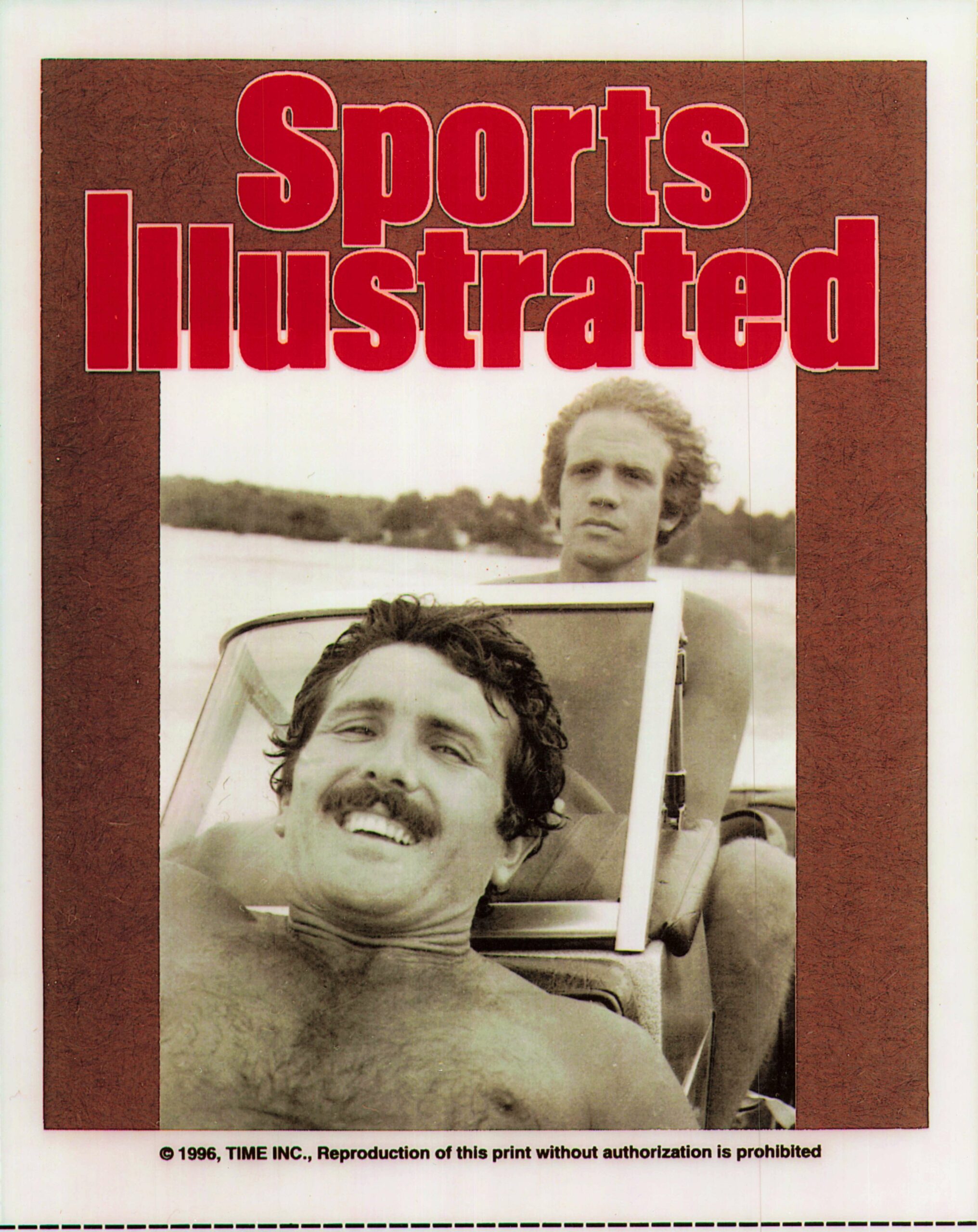 Sports Illustrated cover with two men in a vintage car; foreground man smiles at camera as the SI title appears above in red text.