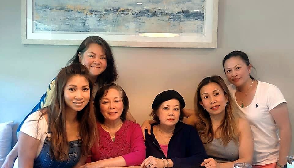 Six women posing together in a living room, smiling at the camera.